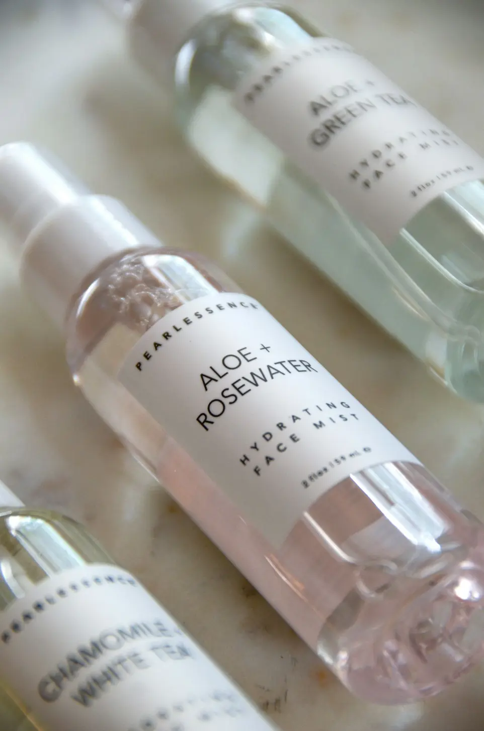 clear glass bottle on white table pearlessence alow + rosewater hydrating face mist