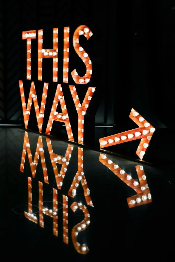 a lighted sign that says this way next to it