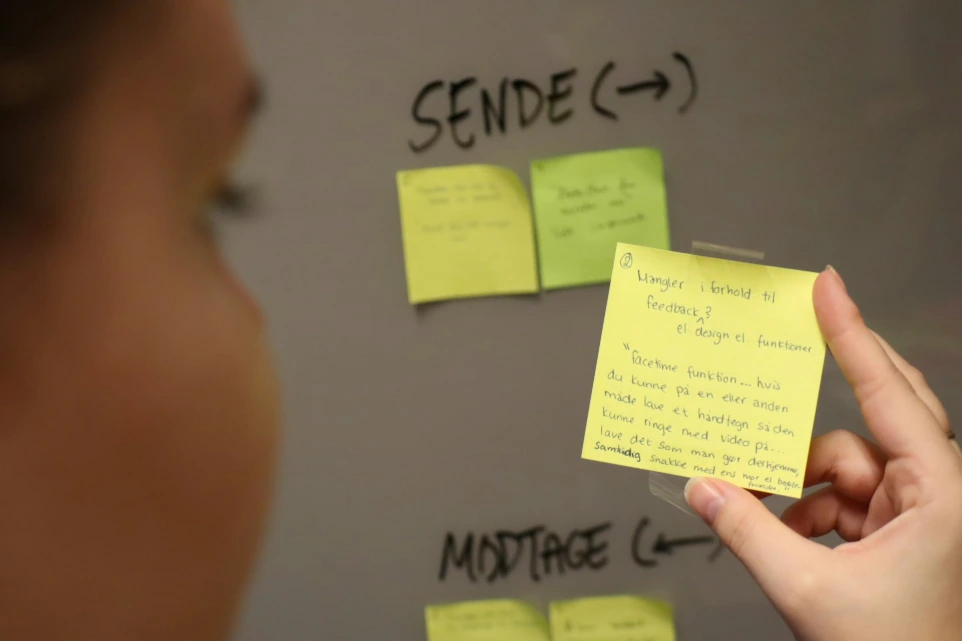 a person holding a post it note in front of a whiteboard